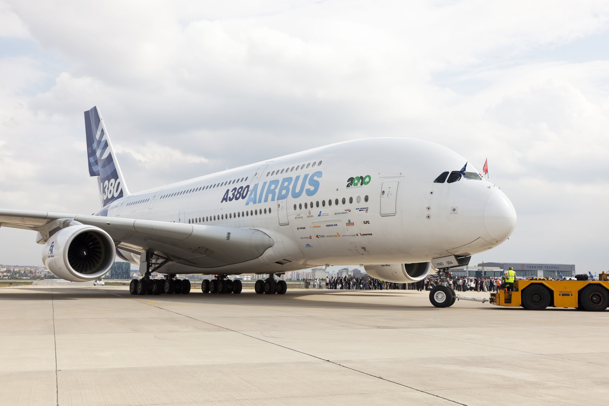 Een Airbus A380 op de tarmac met op de achtergrond vliegtuigwaarnemers.