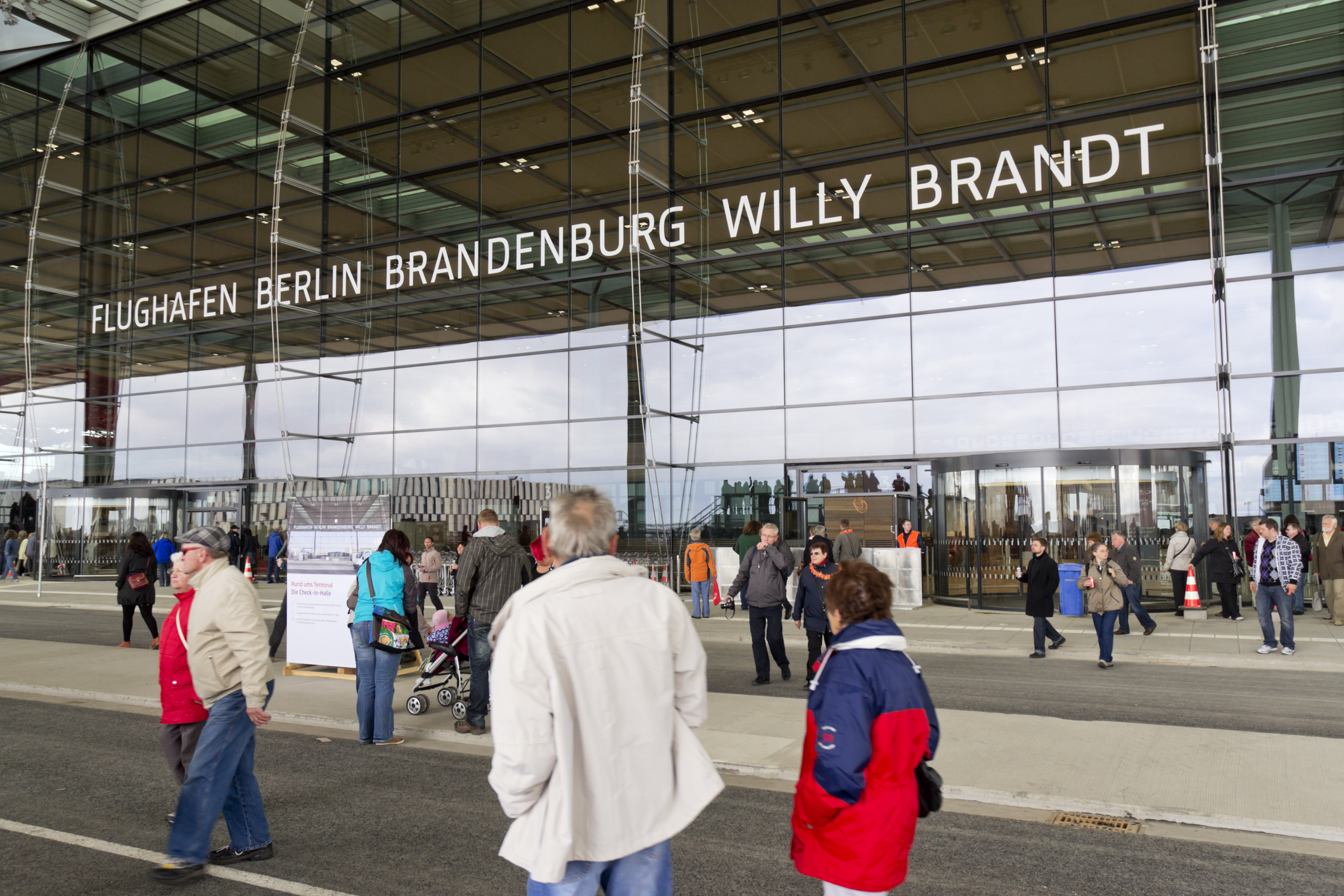 De hoofdingang van Berlin Brandenburg Willy Brandt Airport met veel mensen op de voorgrond.