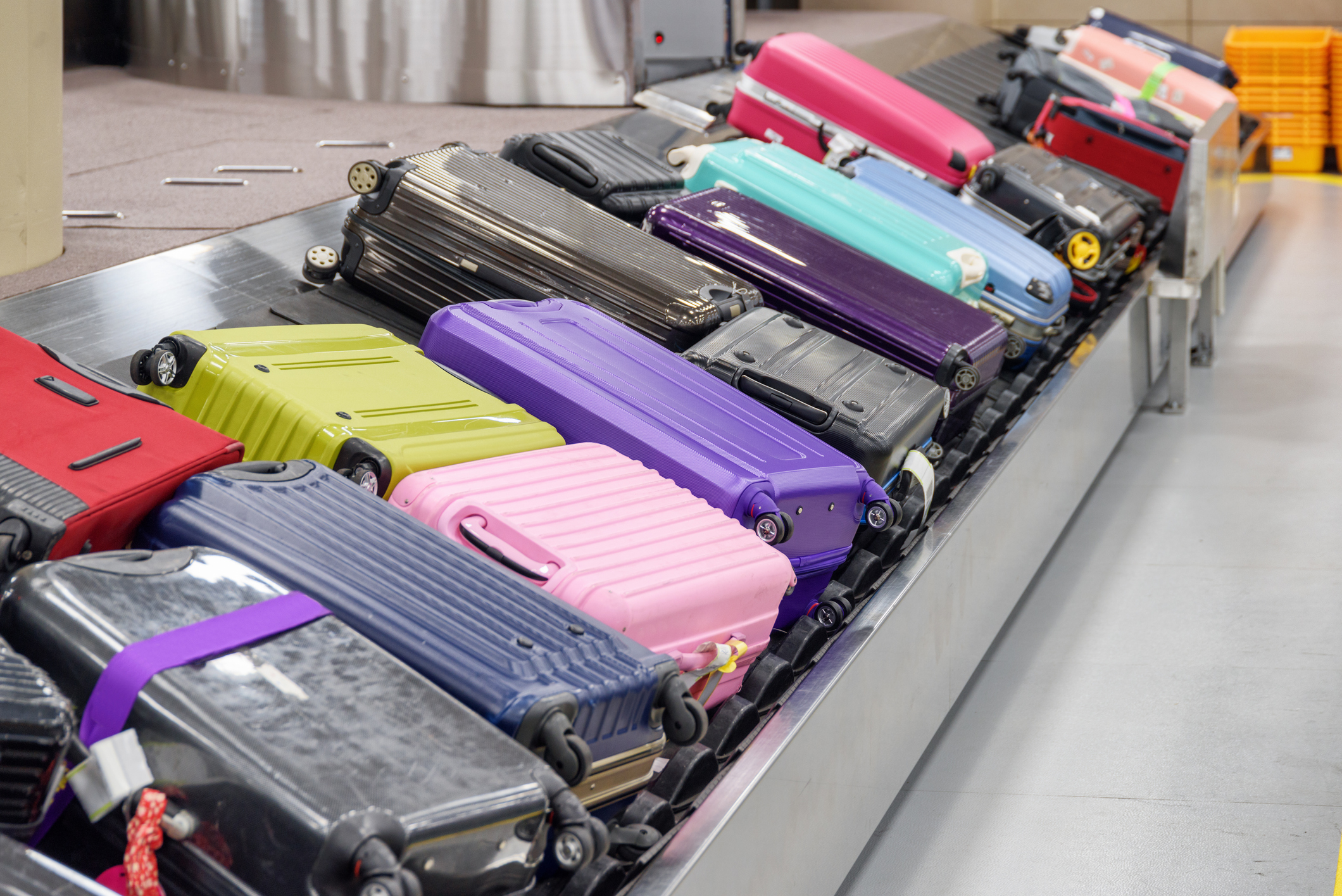 Koffers stapelen zich in grote hoeveelheid op op een bagageband.