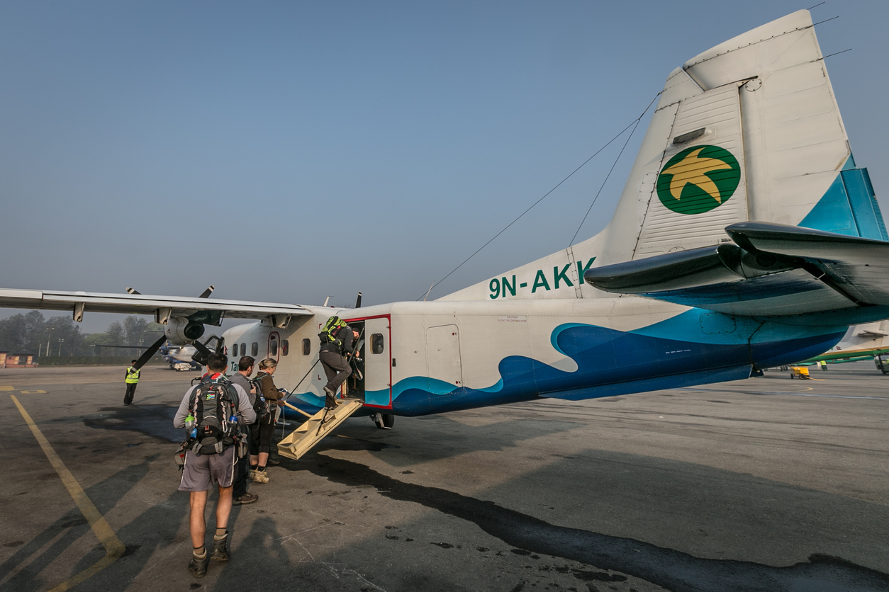 Een propellervliegtuig in Nepal, passagiers stappen net in.