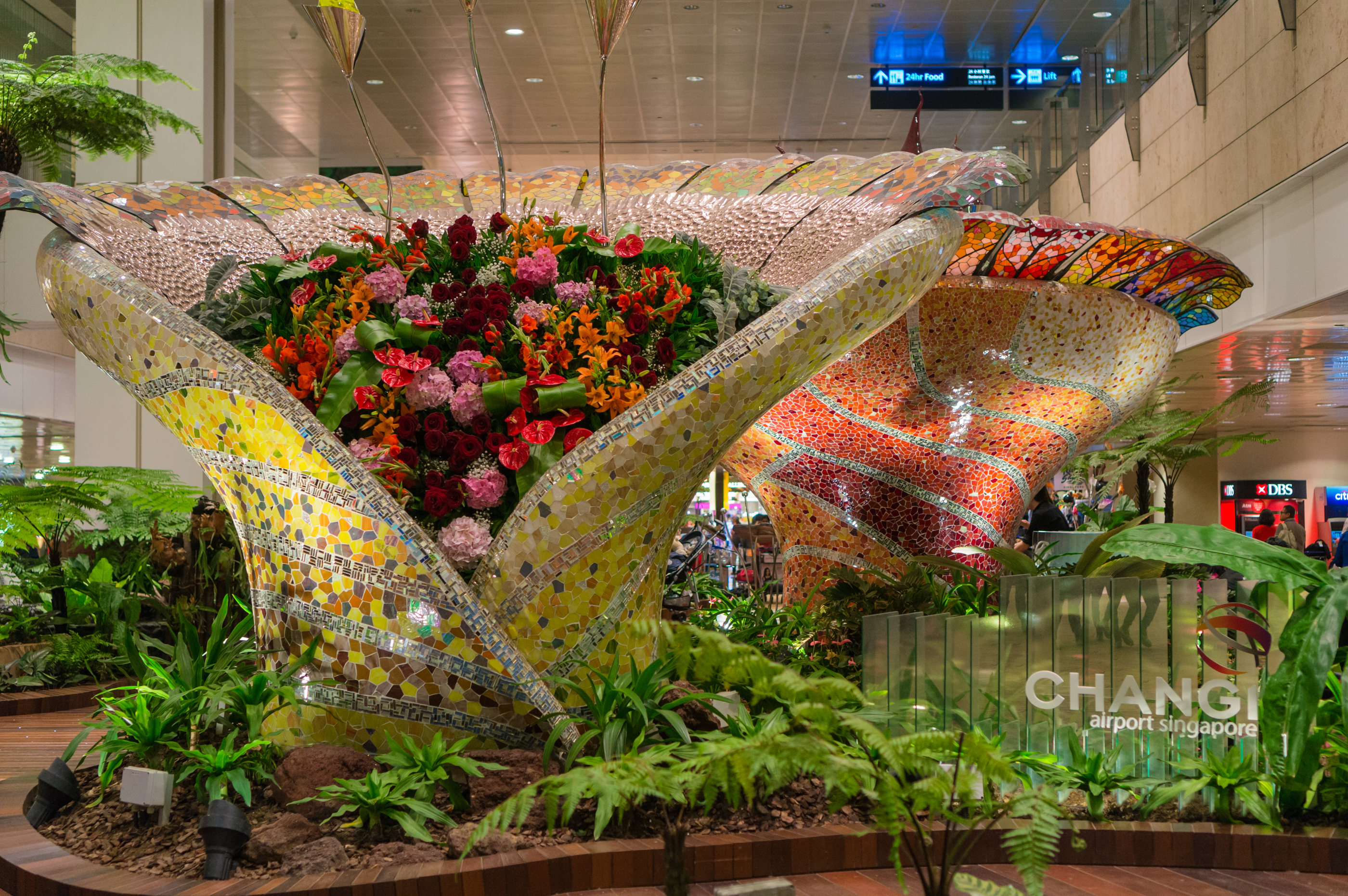 Twee zeer grote bloembakken versierd met sierlijke mozaïeken in Changi Airport.