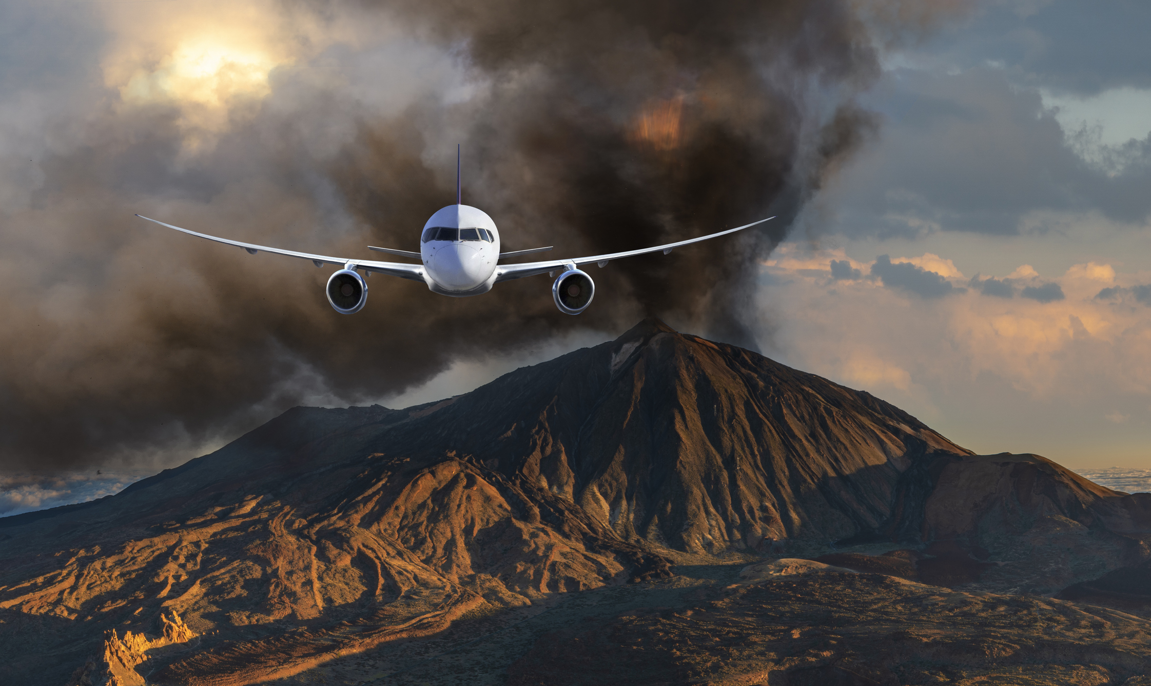 Een vliegtuig vliegt richting de camera, op de achtergrond is een aswolk en vulkaanlandschap te zien.