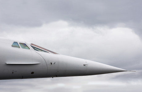 De neus en cockpit van een Concorde voor een bewolkte lucht.