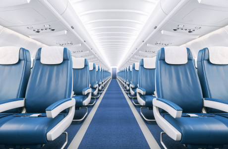 Leeg gangpad in volledig leeg vliegtuig met blauw tapijt, wit plafond en blauw en wit lederen zetels
