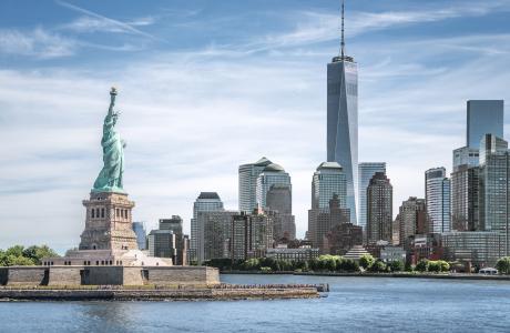 Gezicht op een deel van Manhattan, met het Vrijheidsbeeld op de voorgrond en One World Trade Center op de achtergrond.