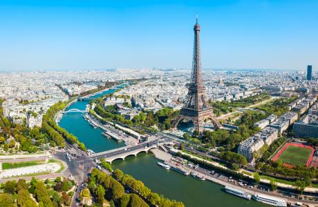 Een luchtfoto van Parijs, op de voorgrond zie je de Eiffeltoren en de rivier de Seine, op de achtergrond strekt de stad zich uit.