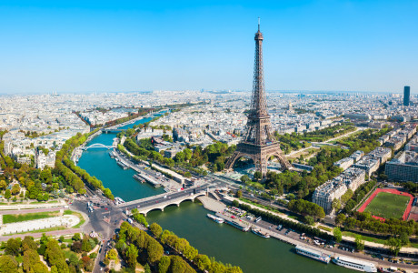 Een luchtfoto van Parijs, op de voorgrond zie je de Eiffeltoren en de rivier de Seine, op de achtergrond strekt de stad zich uit.