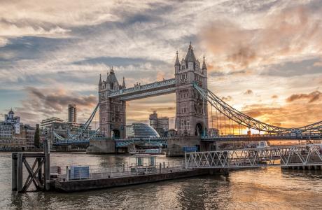 Tower Bridge in Londen tegen een dramatische zonsopgang, met een loopbrug op de voorgrond.