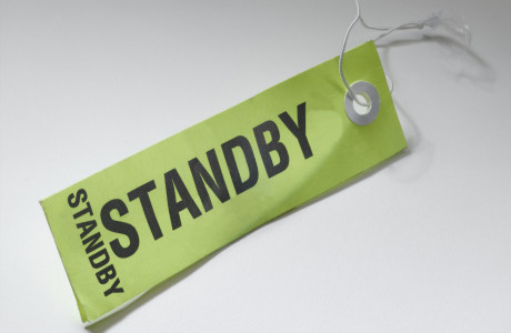 Een bagagelabel met het opschrift "STANDBY" ligt op een wit vlak.