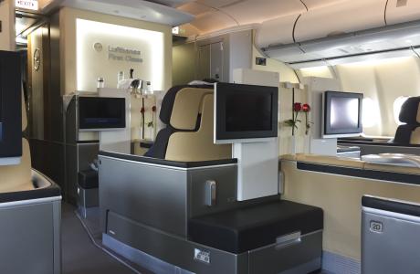 Lufthansa First Class met enkele stoelen en schermen.